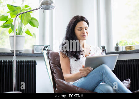 Mid adult woman using digital tablet at home Stock Photo