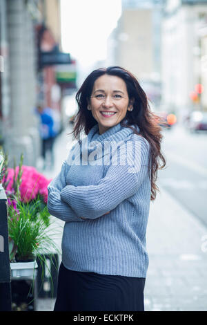 Side view portrait of smiling woman on standing on sidewalk Stock Photo