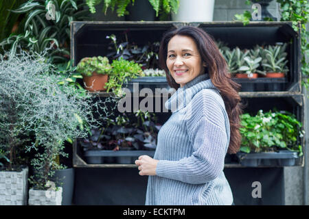 Side view portrait of smiling woman on standing against flower shop Stock Photo