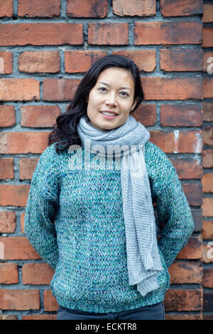 Portrait of woman standing against brick wall Stock Photo