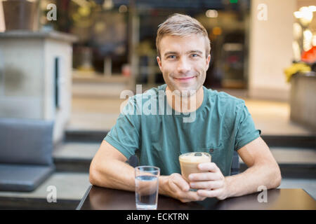 Portrait of smiling young man having coffee in restaurant Stock Photo