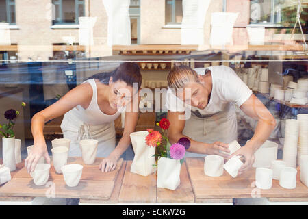 Workers arranging craft products for display in crockery workshop Stock Photo