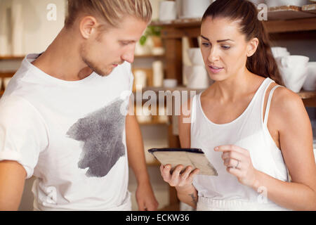 Male worker looking at female colleague using digital tablet at workshop Stock Photo