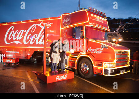 A family being photographed in front of the Coca Cola Truck at Looe in Cornwall. The truck travels around the country each year. Stock Photo