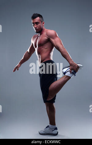 Full length portrait of young man athlete doing stretches exercises Stock Photo