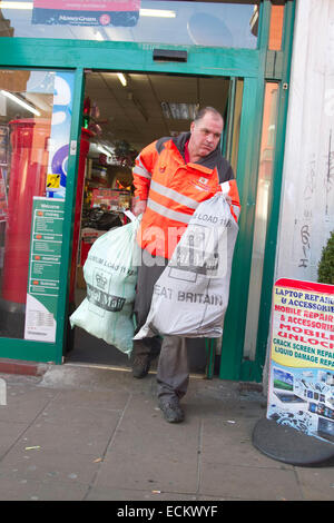 Wimbledon, London, UK. 16th Dec, 2014. A Royal Mail worker carries Christmas post in bags out of a Post Office branch at Wimbledon. Longer queues at the Post Office as people try to get the Christmas post deadline. The longer queues is partly caused by the closure of thousands of Post Office branches across the United Kingdom Credit:  amer ghazzal/Alamy Live News Stock Photo
