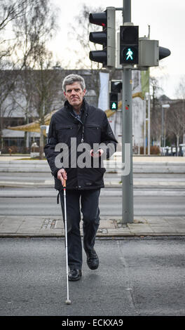 Braunschweig, Lower Saxony, Germany. 16th Dec, 2014. Blind Gerhard Renzel stands at a traffic light, lead aby the traffic-app 'InMoBS' (Inner city mobility support for blind and visually impaired) in Braunschweig, Lower Saxony, Germany, 16 December 2014. 'InMoBS' is supposed to help blind people navigate through traffic. The app was presented the same day. PHOTO: OLE SPATA/dpa/Alamy Live News Stock Photo