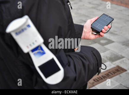 Braunschweig, Lower Saxony, Germany. 16th Dec, 2014. Blind Gerhard Renzel uses the traffic-app 'InMoBS' (Inner city mobility support for blind and visually impaired) on Gerhard Renzel's smartphone in Braunschweig, Lower Saxony, Germany, 16 December 2014. On his arm, Renzel wears a GPS-receiver wich, together with the smartphone, can precisely locate the position. 'InMoBS' is supposed to help blind people navigate through traffic. The app was presented the same day. PHOTO: OLE SPATA/dpa/Alamy Live News Stock Photo