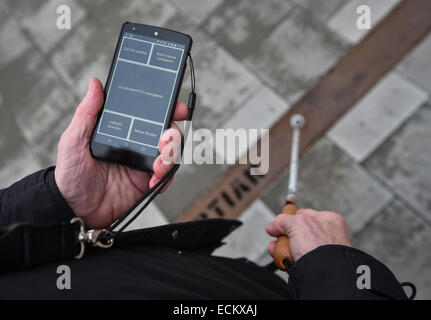 Braunschweig, Lower Saxony, Germany. 16th Dec, 2014. Blind Gerhard Renzel uses the traffic-app 'InMoBS' (Inner city mobility support for blind and visually impaired) on Gerhard Renzel's smartphone in Braunschweig, Lower Saxony, Germany, 16 December 2014. 'InMoBS' is supposed to help blind people navigate through traffic. The app was presented the same day. PHOTO: OLE SPATA/dpa/Alamy Live News Stock Photo