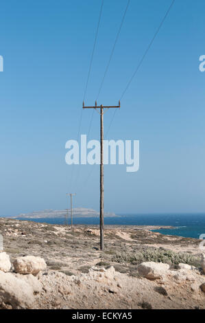 wooden pylons of a power line on the sea coast Stock Photo