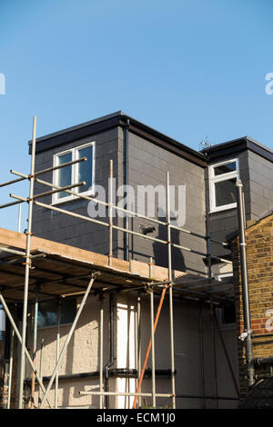 Scaffolding to a newly completed dormer / dormers / dormas / dorm roof extension with slate tile cladding on the roof on a Victorian terraced house in Twickenham. London. UK Stock Photo