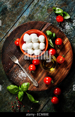 Cherry tomatoes, basil leaves, mozzarella cheese and olive oil for caprese salad. Lots of copy space Stock Photo