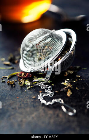 Tea composition with tea strainer on dark background Stock Photo