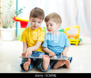 Two boys sitting beside him and read a book Stock Photo