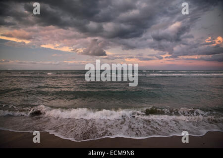 Dark pink clouds at sunset with coral reef waves on Atlantic Ocean beach of Maimon Bay near Puerto Plata Dominican Republic Stock Photo