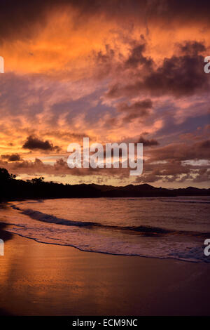 Red clouds at sunset reflecting off wet beach sand of Maimon Bay Riu beach resort Dominican Republic Stock Photo