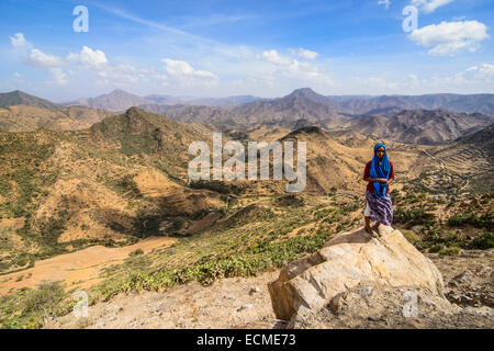 Local woman standing on a rock in front of the mountain scenery along the road from Massawa to Asmarra, Eritrea Stock Photo