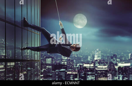 Young man climbing on the high skyscraper Stock Photo