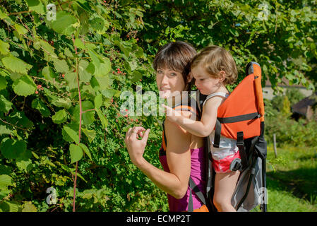 a little girl in a baby carrier walks with his mom in mountain Stock Photo