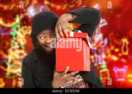 Portrait of African American woman opening gift with holiday lights in background Stock Photo