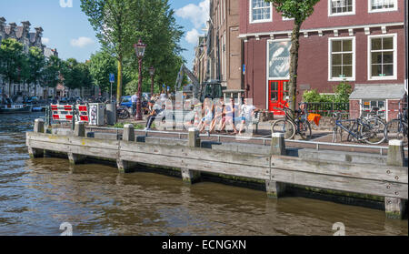 AMSTERDAM - AUGUST 4: people sitting on a canal in the city center of Amsterdam on august 4, 2014 in Amsterdam Stock Photo