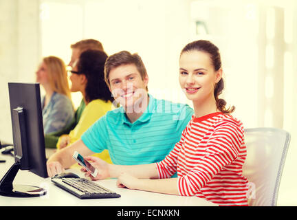 smiling student with smartphone in computer class Stock Photo
