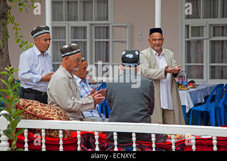 Elderly Uzbek men wearing duppis / kalpoqs praying during a wedding at home, Samarkand, Uzbekistan Stock Photo
