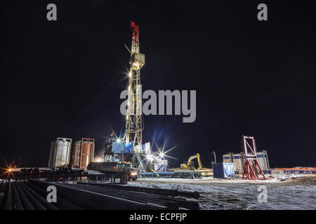 A drilling rig extracting natural gas operates through the night near Wildhay River in the Fox Creek area of northern Alberta in Canada's Oilfields Stock Photo