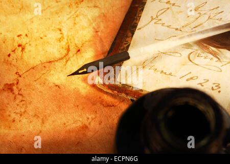 Old book with feather and inkpot in closeup Stock Photo