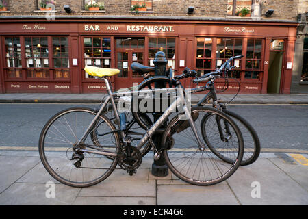 Bicycles locked on the pavement on Brushfield Street outside restaurant in Spitalfields East London UK  KATHY DEWITT Stock Photo