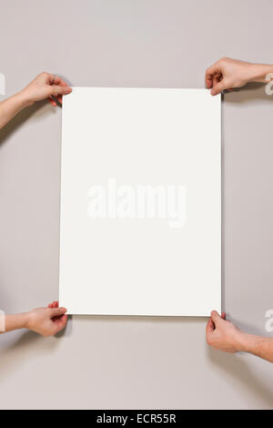 Young woman and man holding a blank poster on light beige-colored background Stock Photo