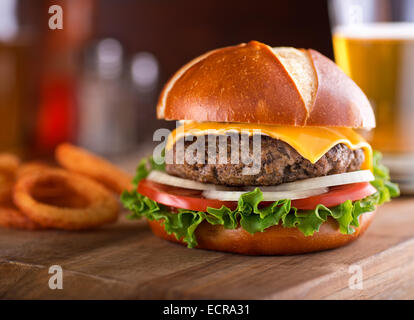 A delicious gourmet cheeseburger on a pretzel bun with lettuce, onion, and tomato. Stock Photo