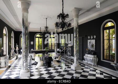 Mirrored pillars in orangerie style room with Panton S chairs and black and white floor tiles Stock Photo