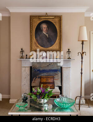 Gilt framed portrait above marble fireplace adorned with candle holders Stock Photo