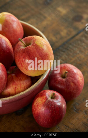 Fresh red apples in a bowel on a rustic wooden table. Stock Photo