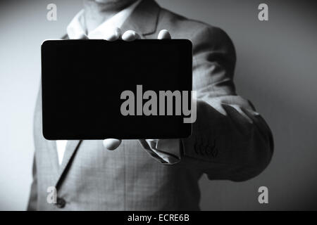 The image displays an individual dressed in a suit holding a tablet computer. Only the person's neck to waist is visible in the Stock Photo
