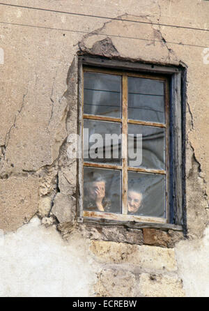 Two elderly women seen through the window of his ruinous house, what happens on the street of a Castilian village on July, 1978, Stock Photo