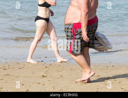 Obese man walking on beach Stock Photo