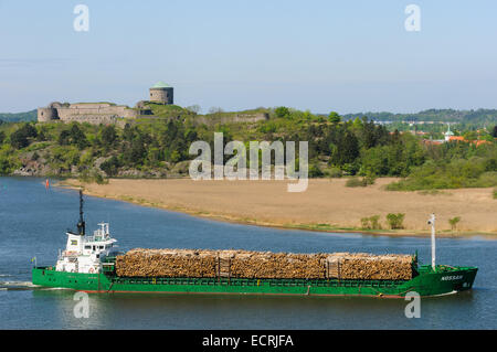 Ship carrying lumber traveling on the water past a castle Stock Photo