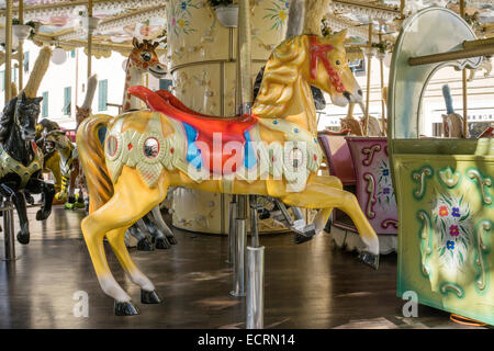 plumed golden molded resin old fashioned type carousel horse on carousel inside gateway to old Roman walled city of Lucca Italy Stock Photo