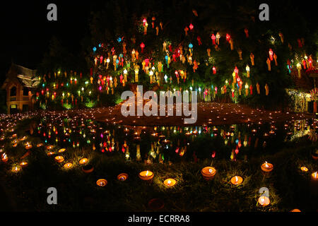 Lanterns and candles reflected in a pool with a Buddha stature for the Loy Krathong Festival at Wat Phan Tao Temple in Chiang Ma Stock Photo