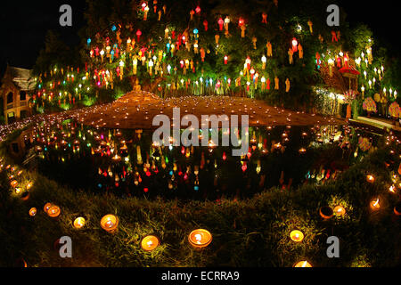 Lanterns and candles reflected in a pool with a Buddha stature for the Loy Krathong Festival at Wat Phan Tao Temple in Chiang Ma Stock Photo