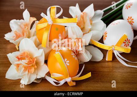 Easter eggs and daffodils on a wooden table Stock Photo