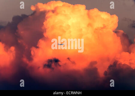Airplane flies through dramatic red clouds Stock Photo