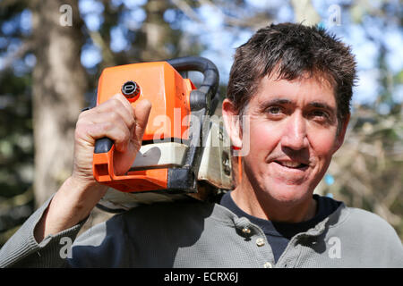 A man with a chainsaw doing spring clean up at his cottage on the Victoria day weekend in Northern Ontario Canada Stock Photo