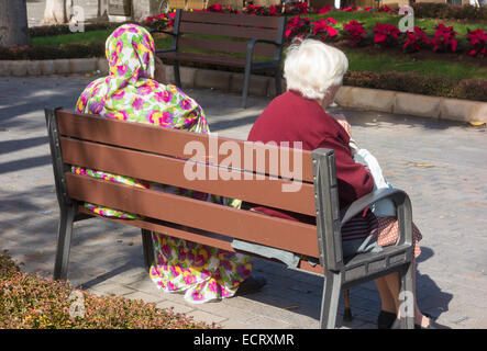 Elderly Spanish woman and woman from Western Sahara sitting on seat in Las Palmas, Gran Canaria, Canary Islands, Spain Stock Photo