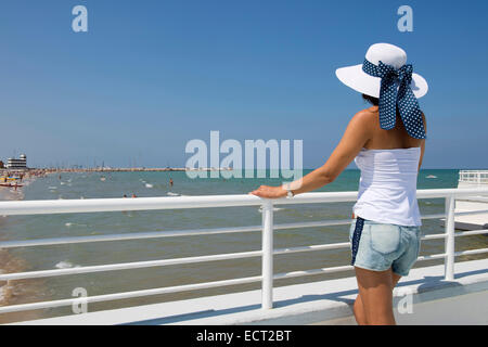 Woman with hat standing at railing on the beach, Adriatic, Senigallia, Province of Ancona, Marche, Italy Stock Photo