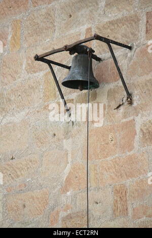 Old bell and rope hanging on a brick wall Stock Photo