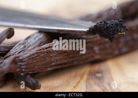 vanilla pod on olive board with beans on knife, close up photo Stock Photo