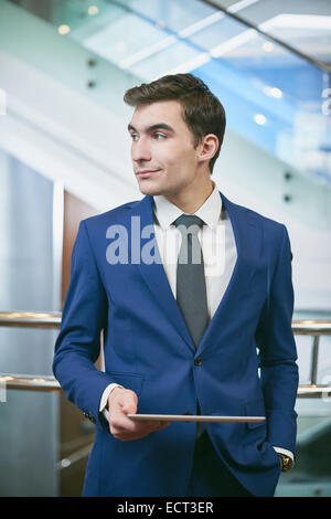 Young businessman with digital tablet looking aside Stock Photo
